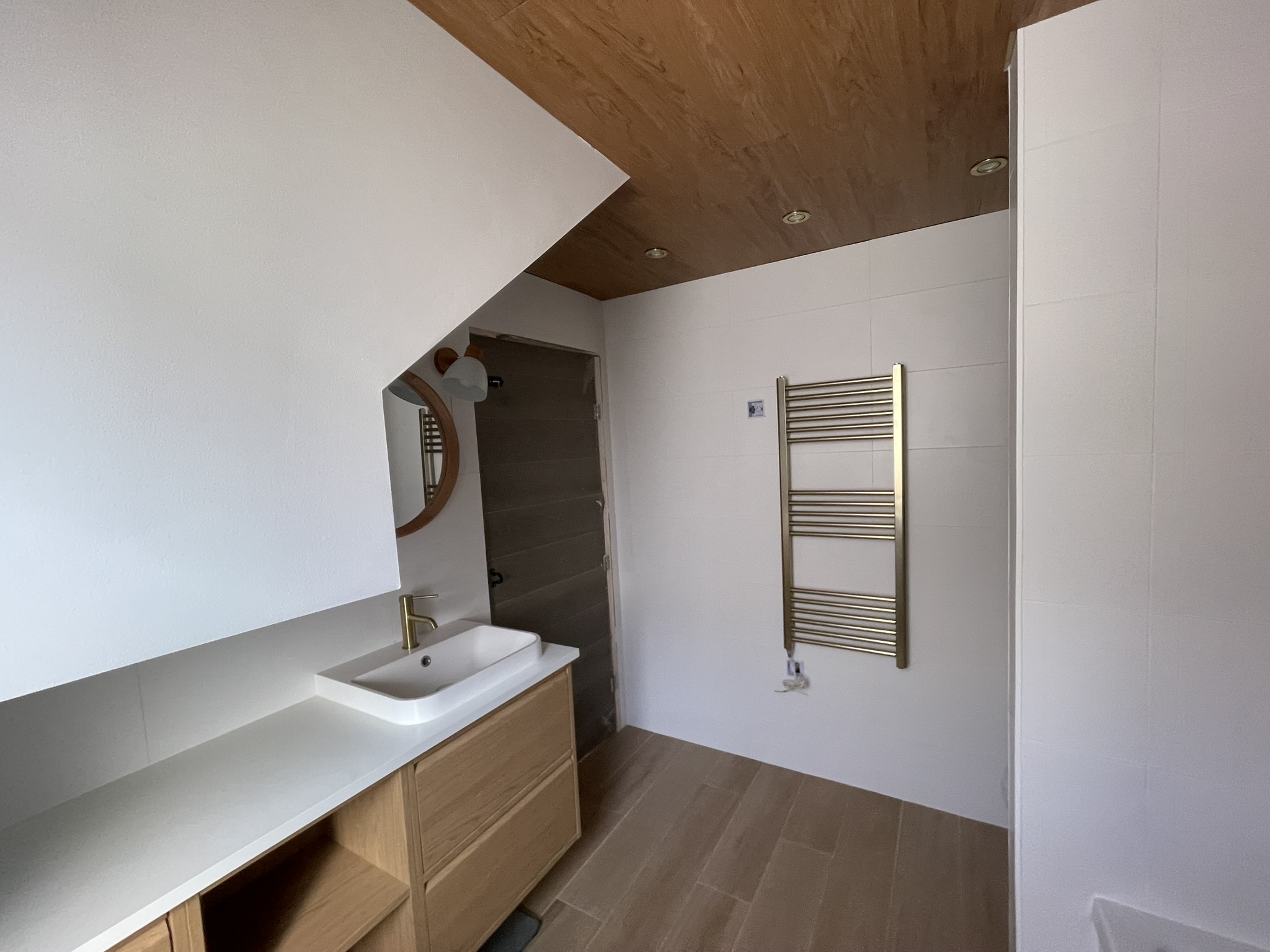 Loft bathroom with gold heated towel rail and oak vanity unit