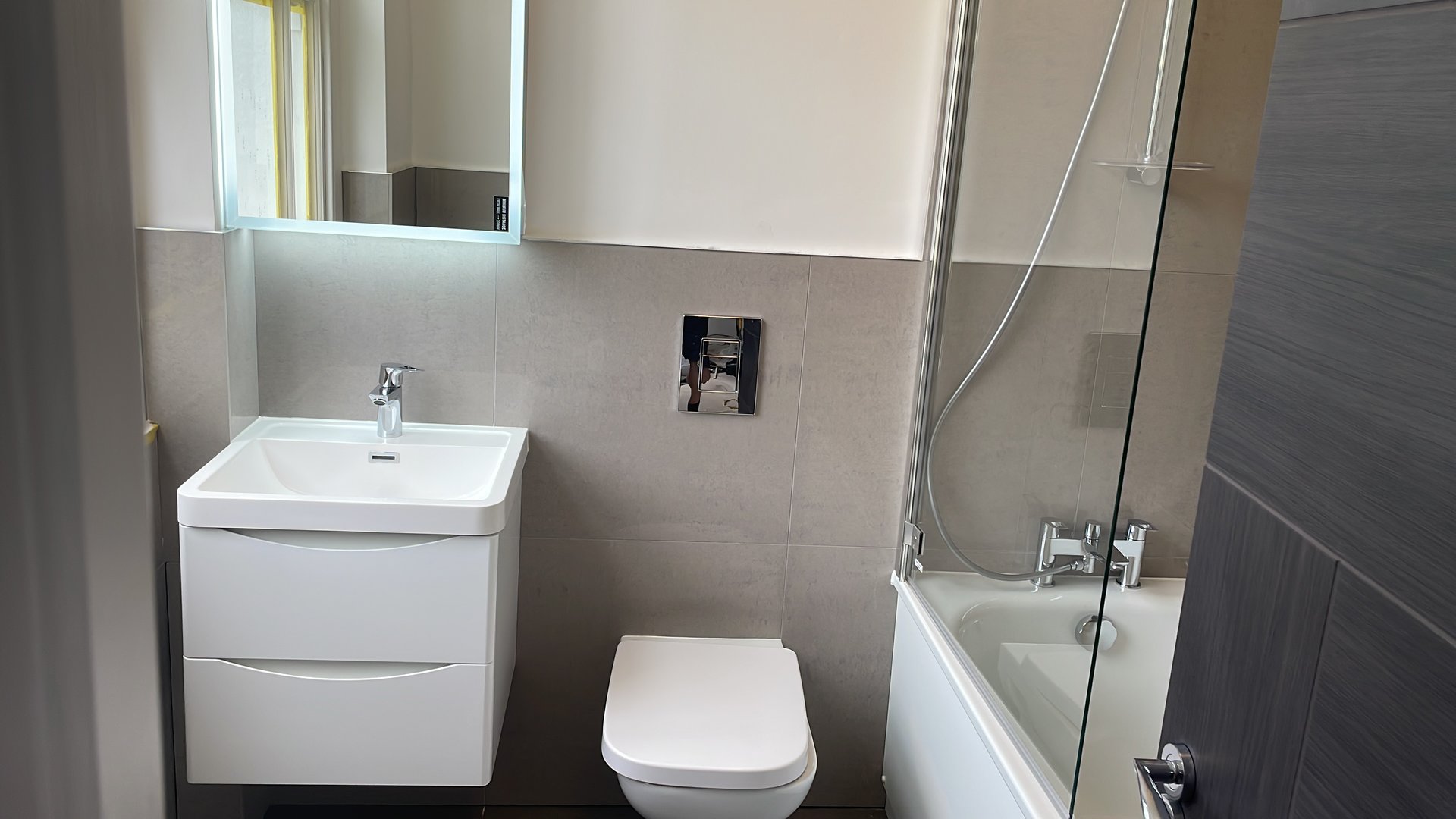 Modern bathroom with LED illuminated mirror, freestanding bath and chrome fixtures by KDB Home Solutions