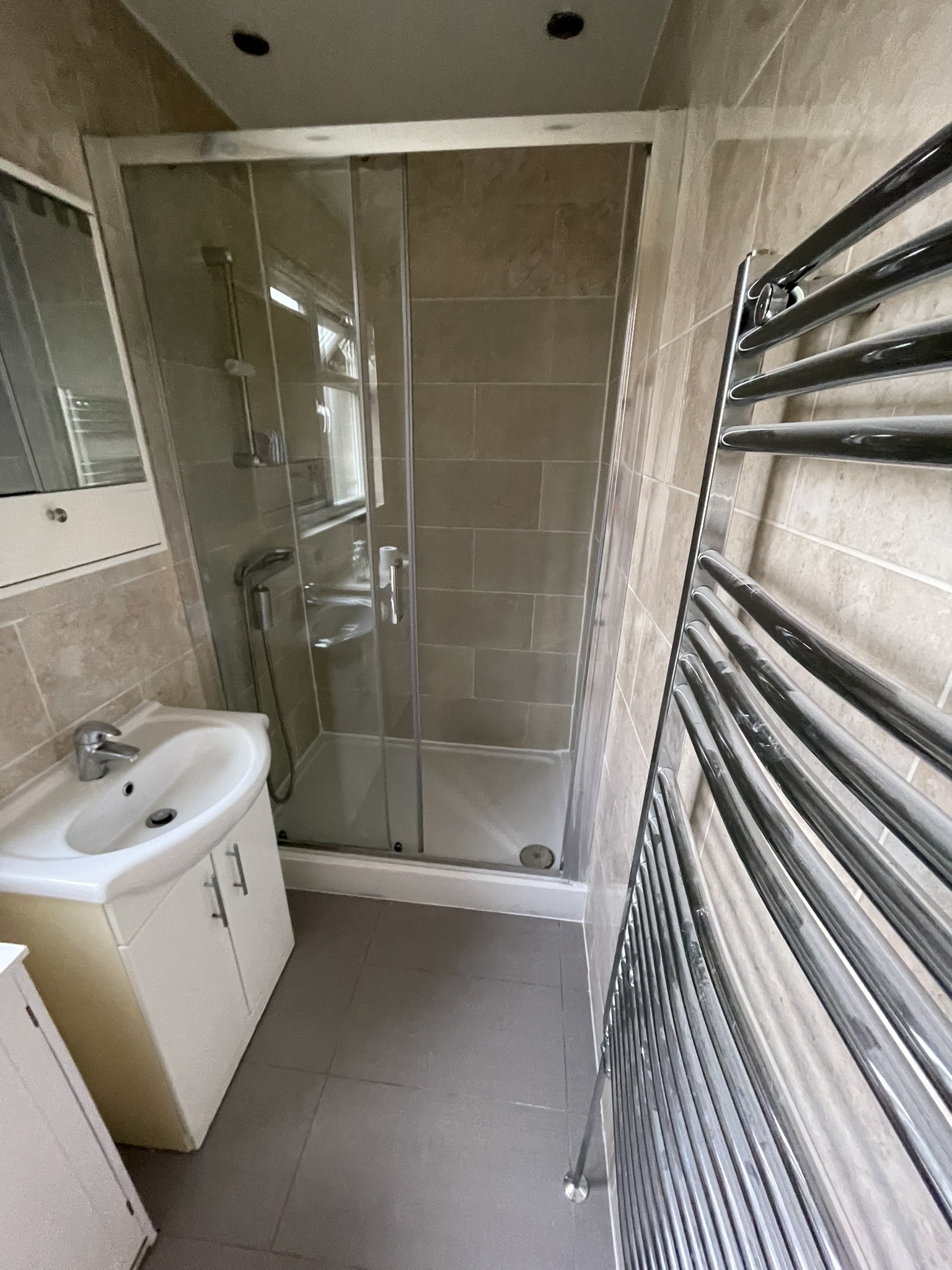Compact shower room with travertine-effect tiles and chrome fixtures