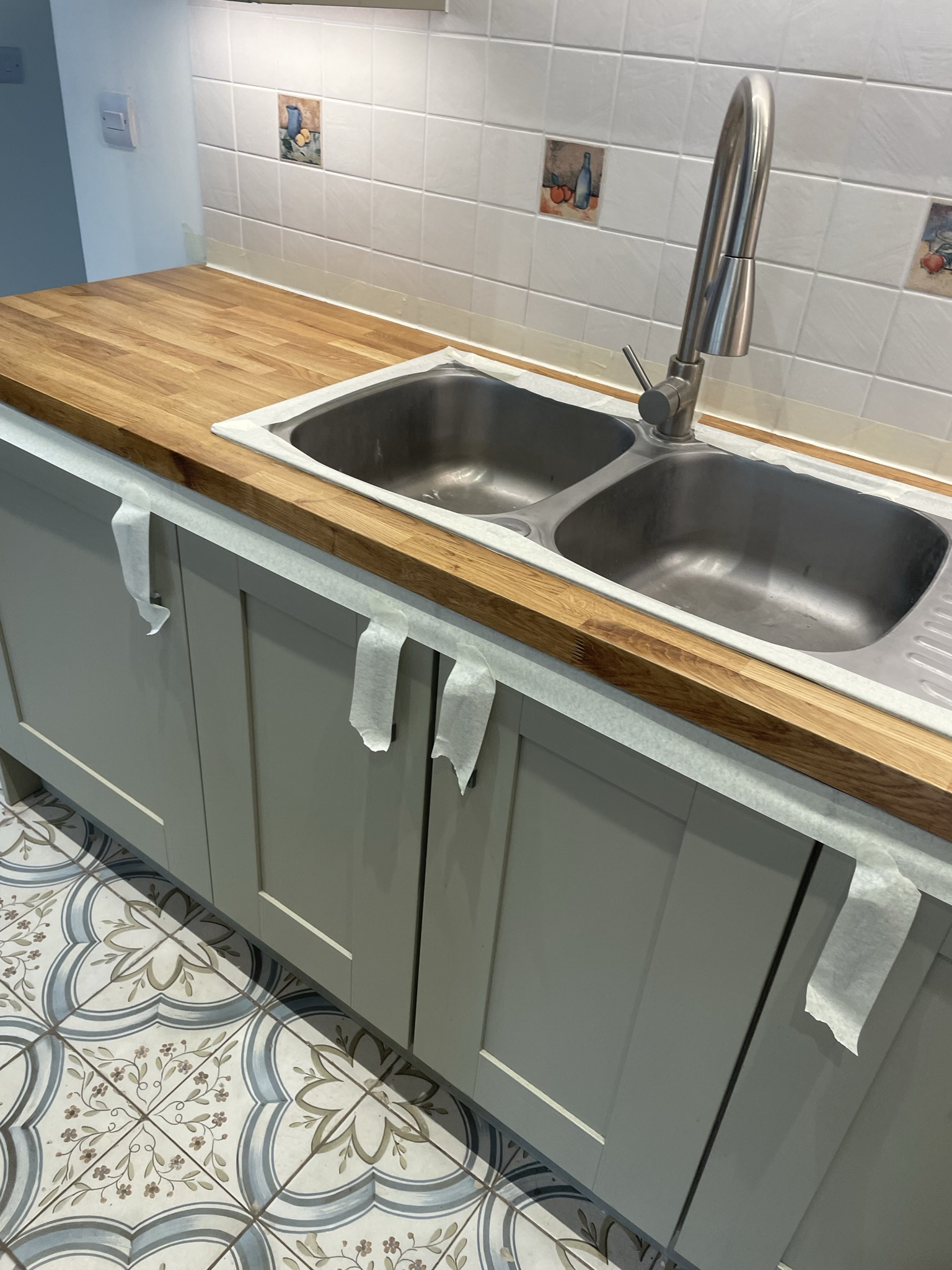 Grey shaker kitchen with solid oak worktop, stainless steel double sink and ornate patterned floor tiles by KDB Home Solutions