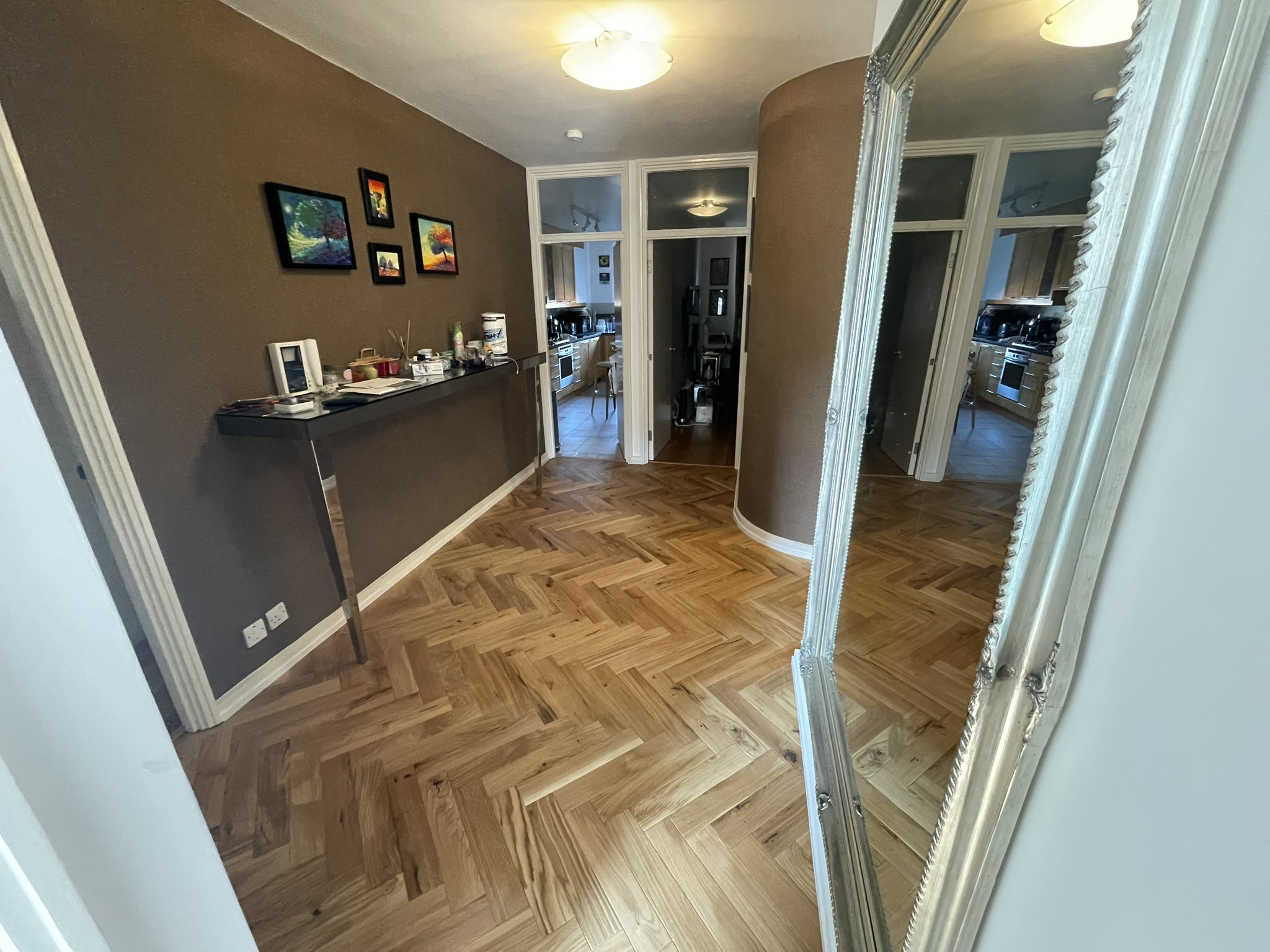 Open plan living room with herringbone oak parquet flooring and large decorative mirror by KDB Home Solutions