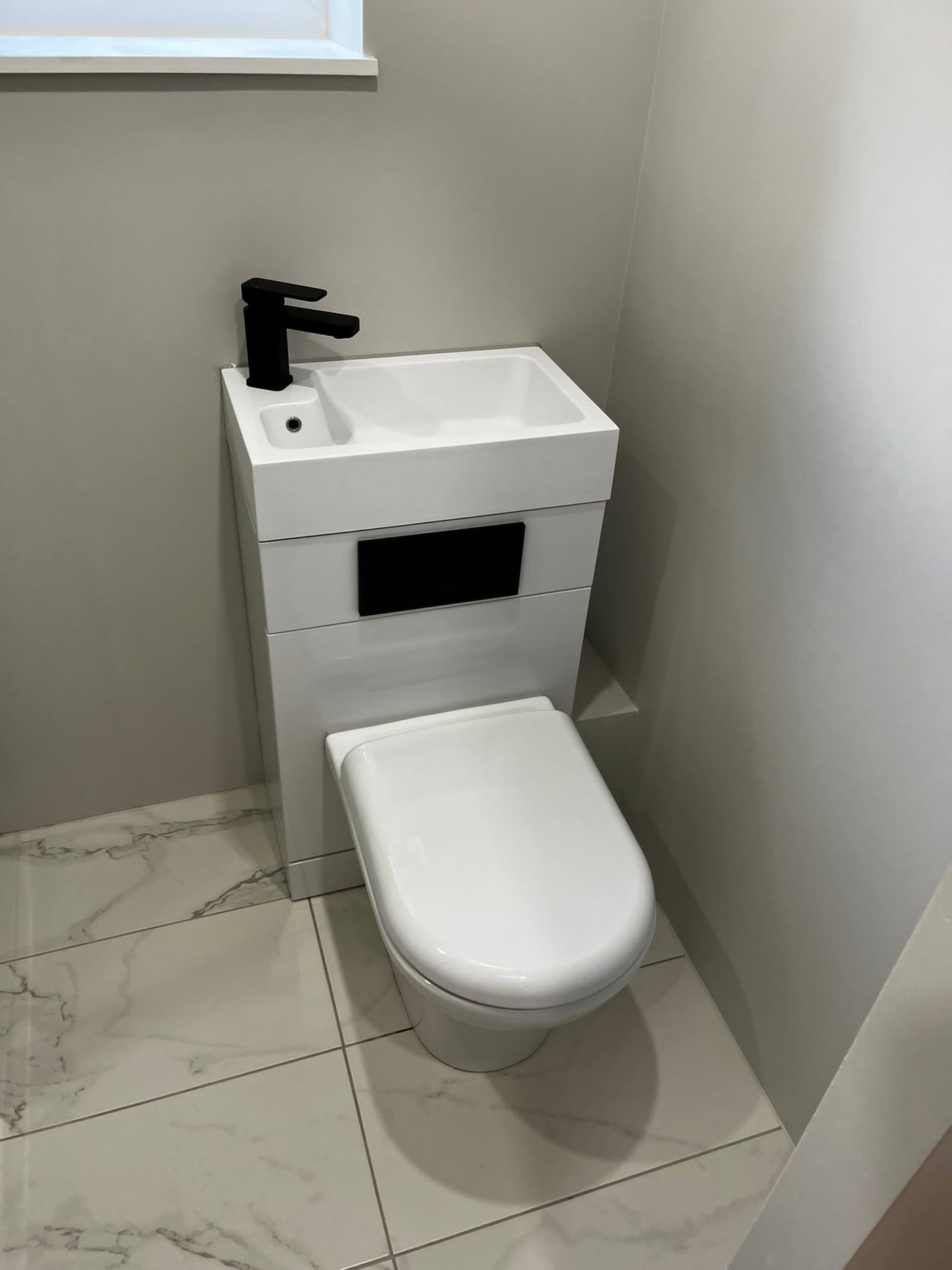 Compact cloakroom WC with marble-effect floor tiles, wall-hung toilet and matte black tap by KDB Home Solutions