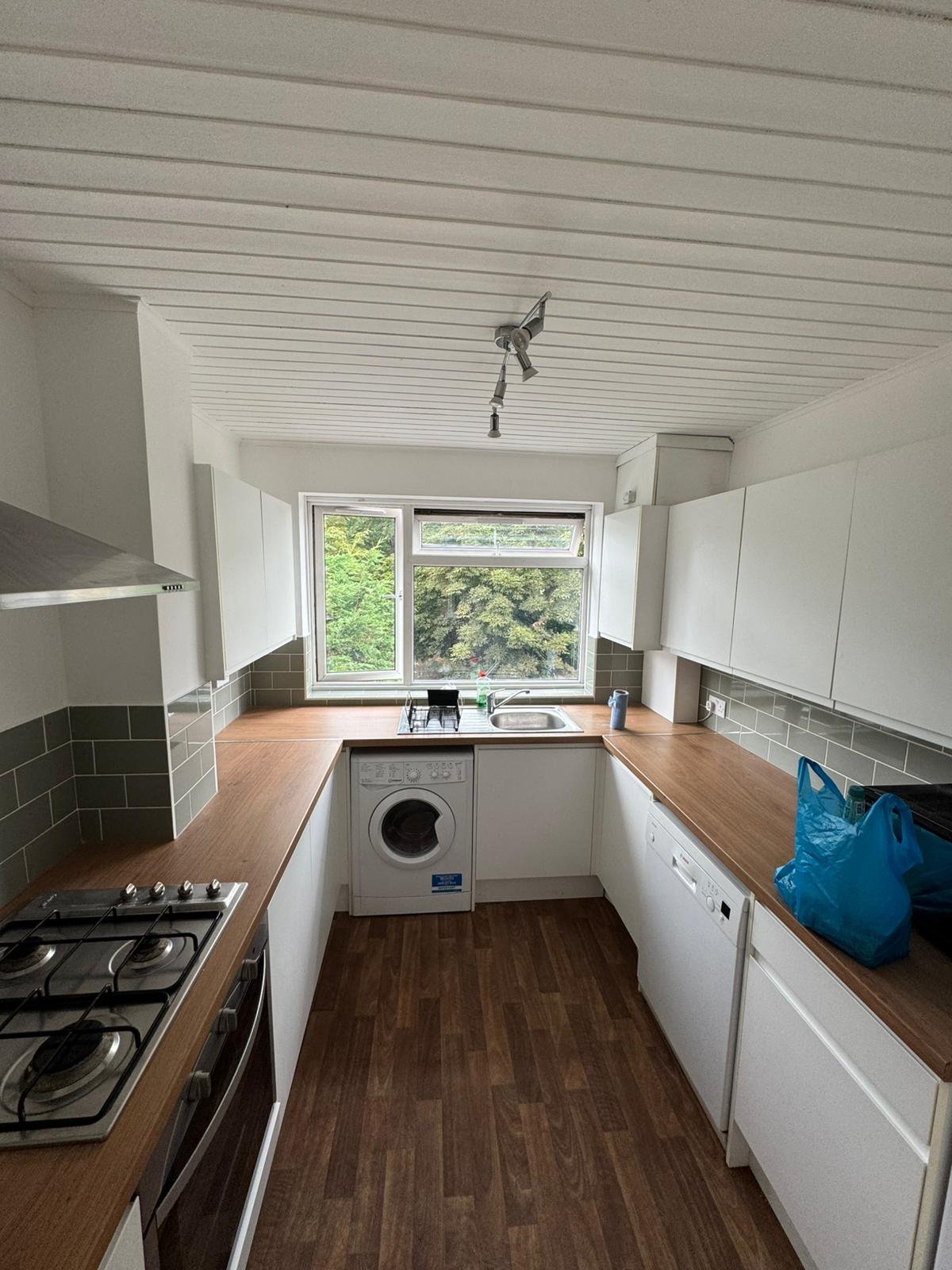 Completed white kitchen with oak worktop, grey metro tile splashback and integrated appliances by KDB Home Solutions