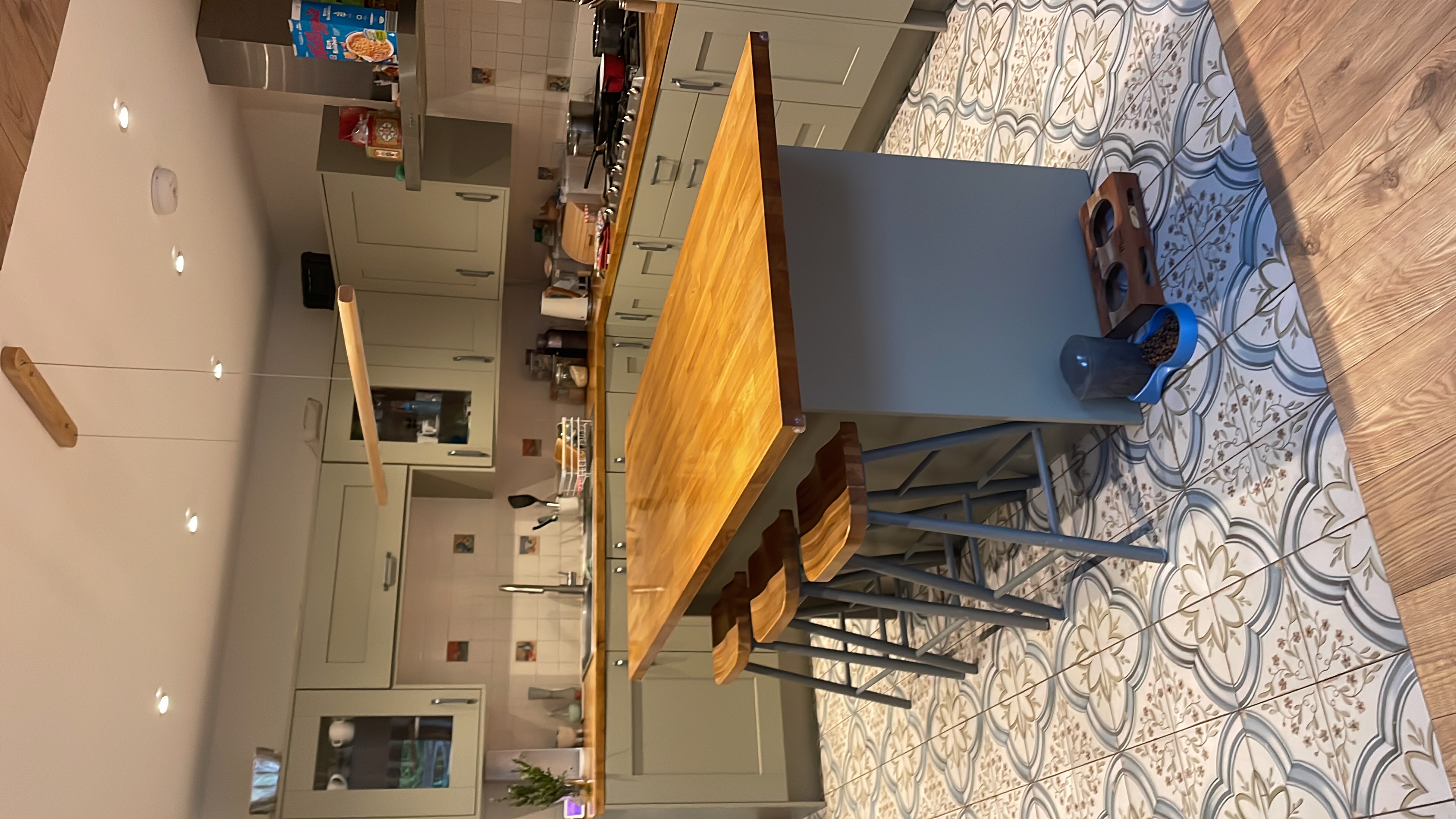 Shaker kitchen full room view with breakfast island, ornate patterned floor tiles and grey-green units