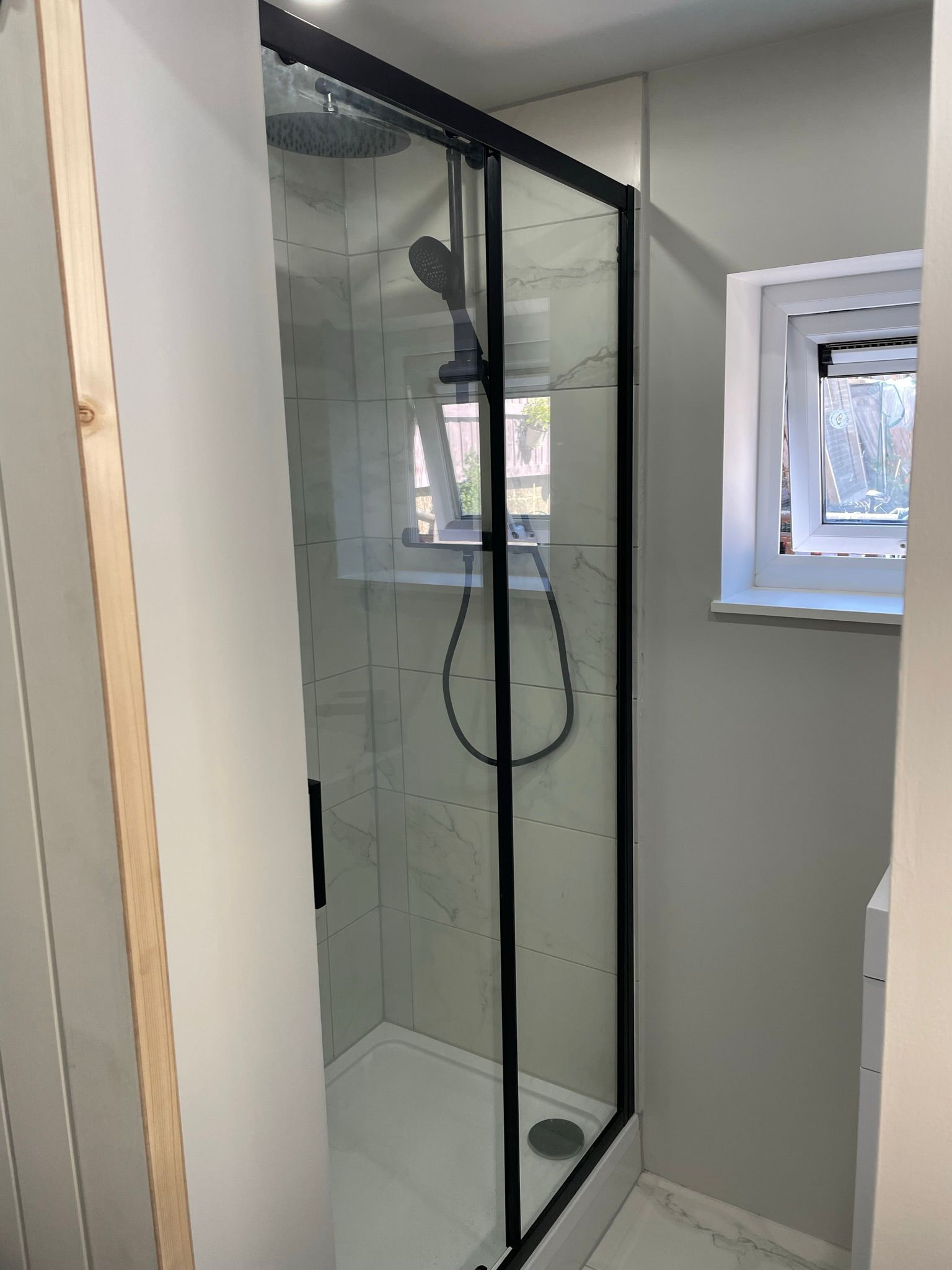 Walk-in shower with black frame and marble-effect porcelain tiles