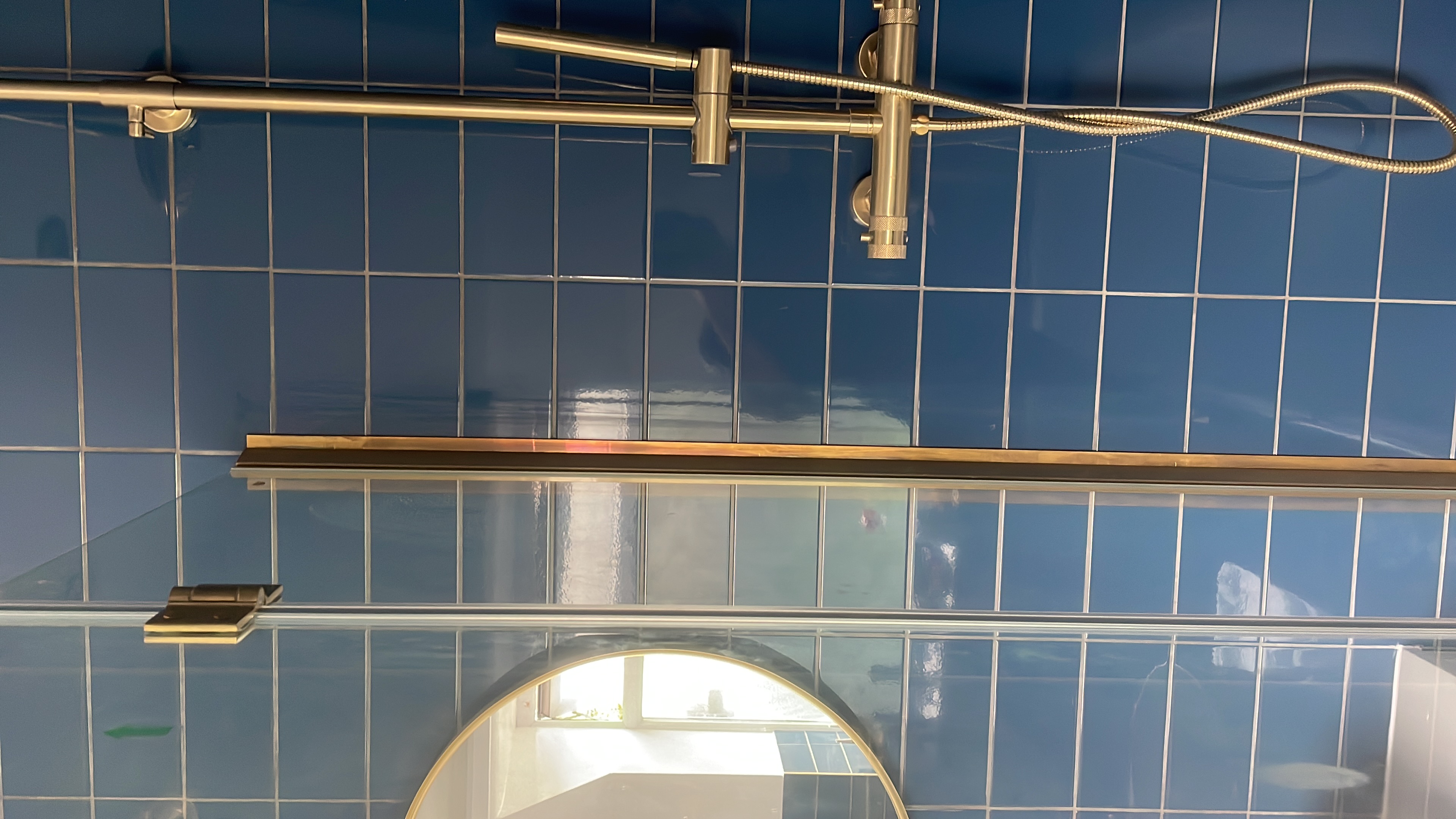 Detail of blue wall tiles and brass shower rail in bathroom renovation
