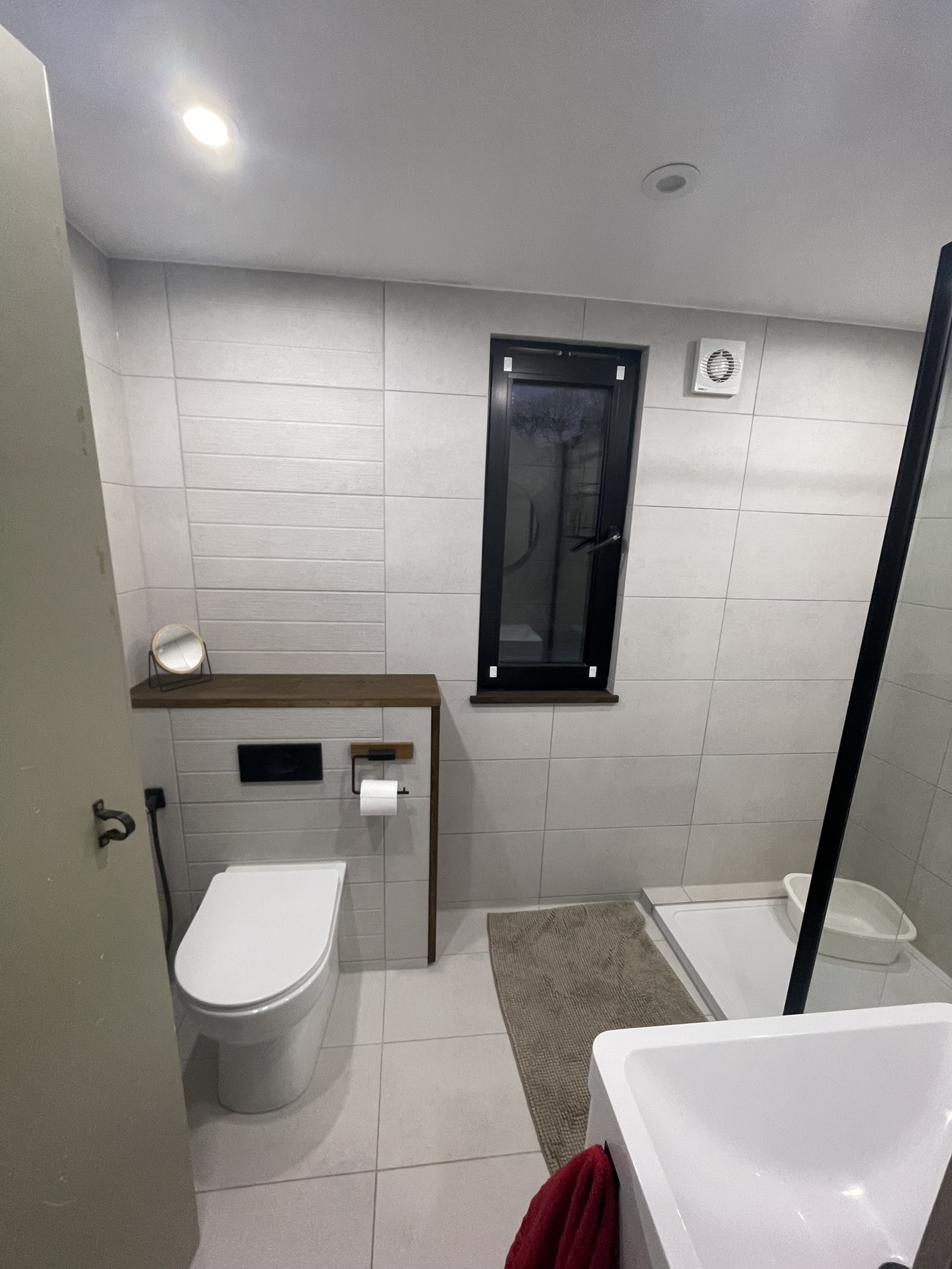 Full view of modern bathroom with black fixtures, wall-hung toilet and walk-in shower
