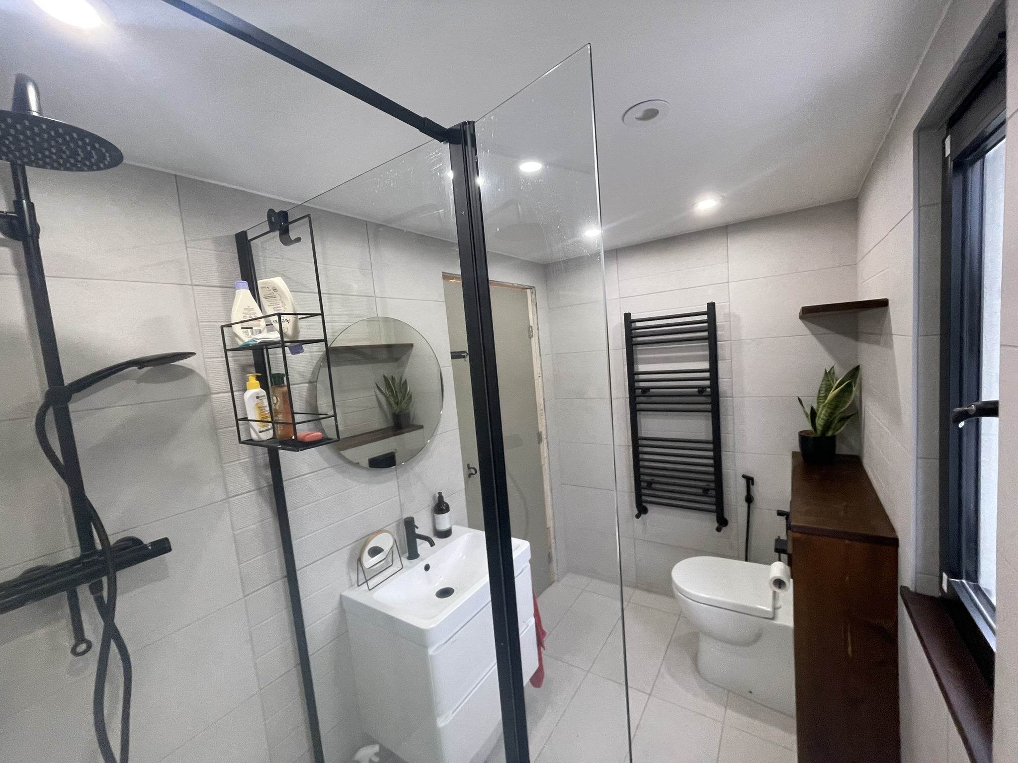 Walk-in shower with black frame, matte black rain head and handheld shower by KDB Home Solutions