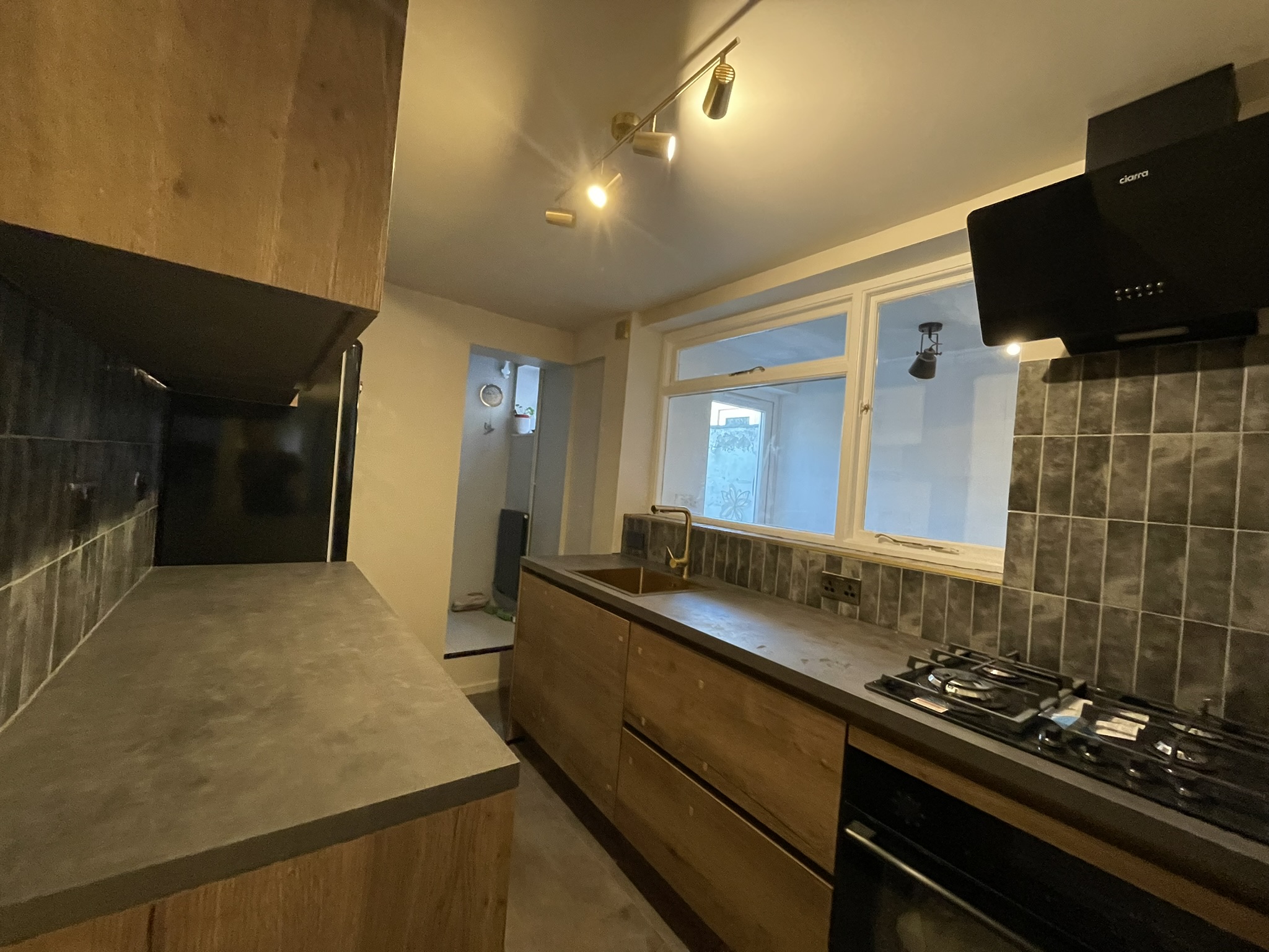 Industrial kitchen renovation with dark oak cabinets, slate-effect worktop and gold tap