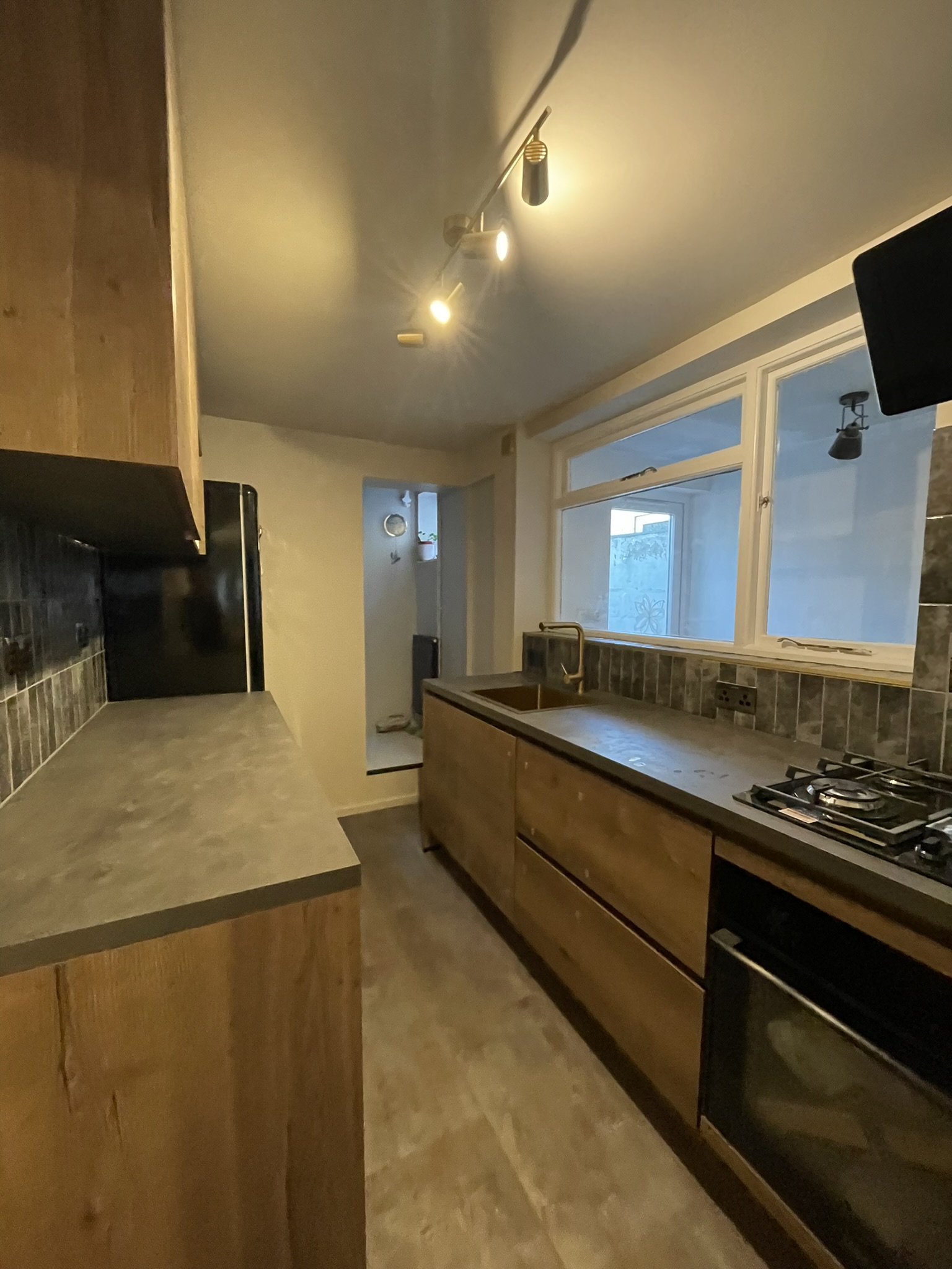 Industrial kitchen full layout with oak cabinets, track lighting and stone tile splashback